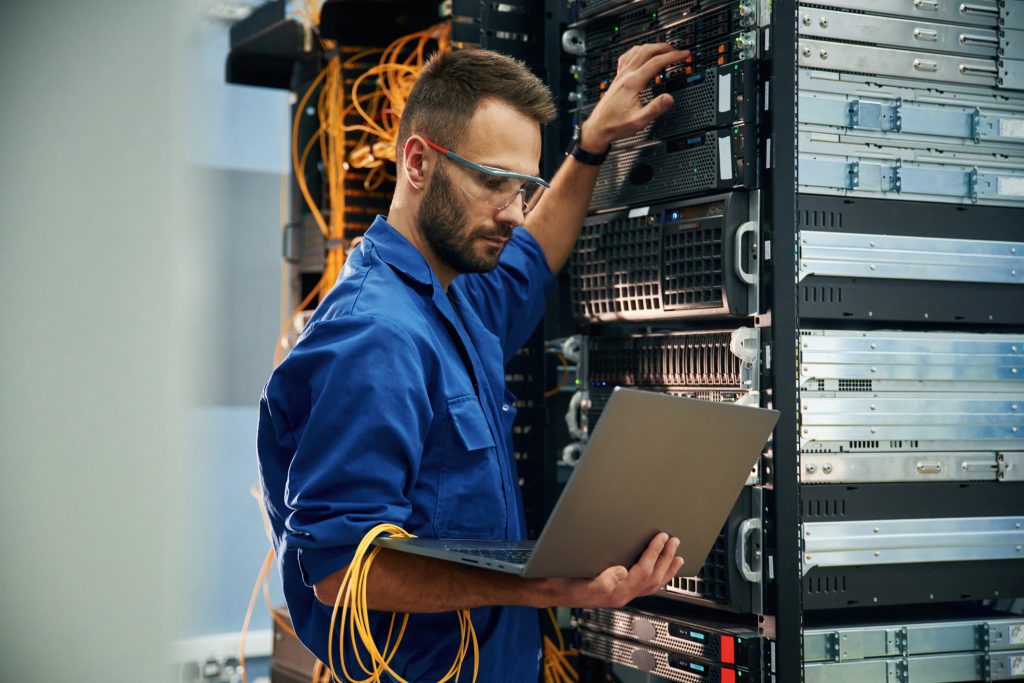 Man is working with internet equipment and wires in server room.